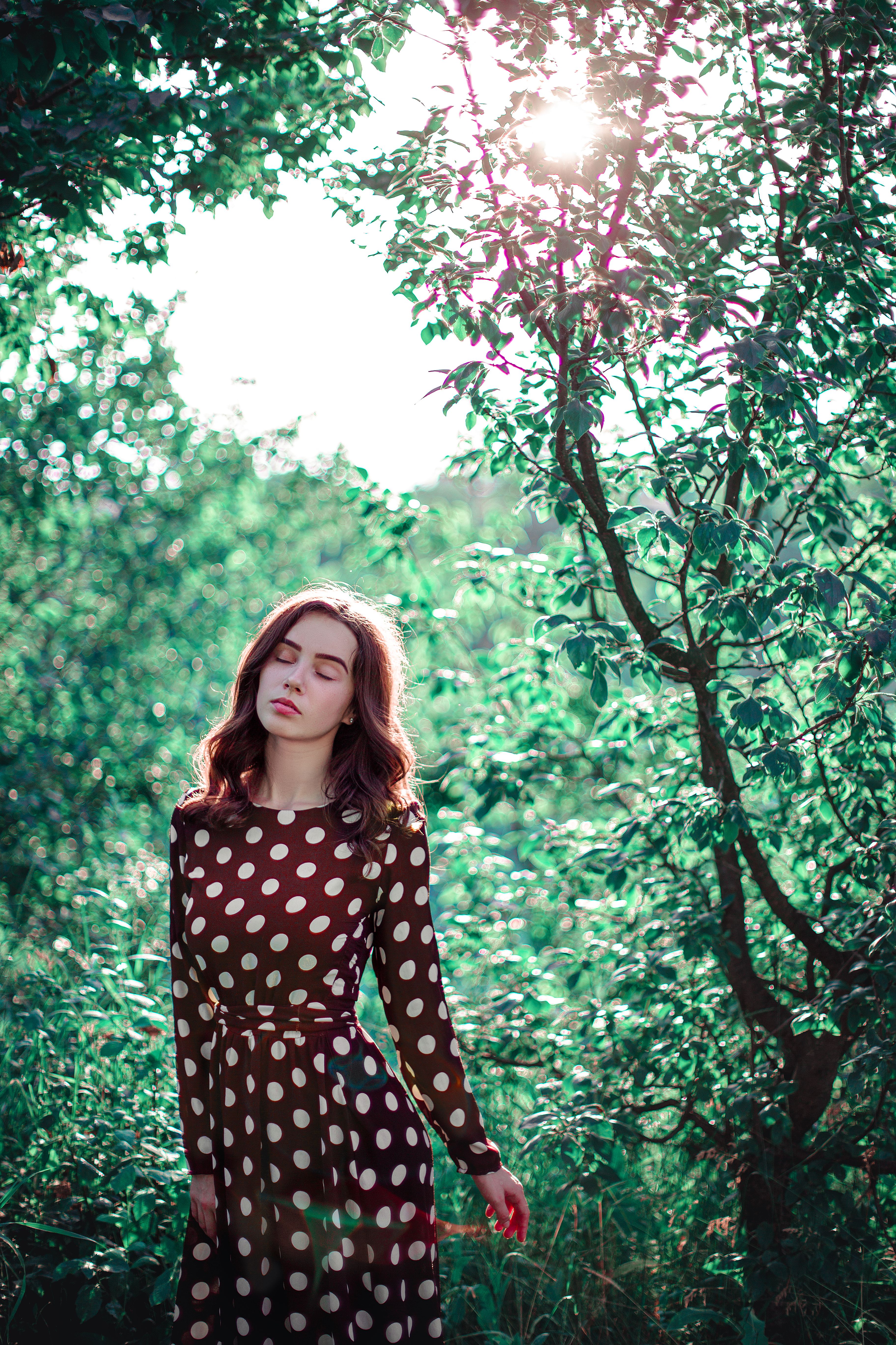 Woman in Polka Dot Dress Surrounded by Summer Greenery · Free Stock Photo