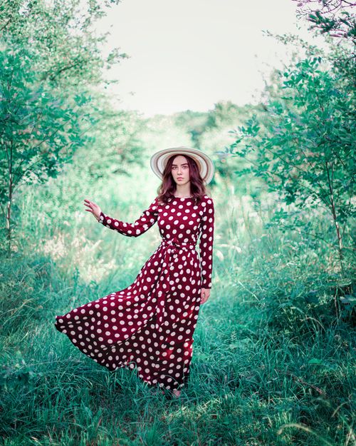 Free Stylish woman in vintage polka dot dress in lush summer greenery, Ukraine. Stock Photo