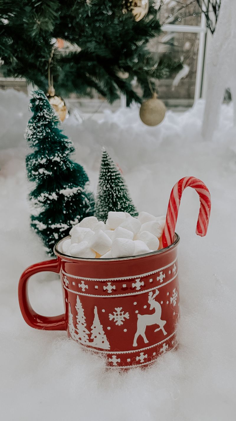 Mug of hot chocolate topped with marshmallows on a festive winter table
