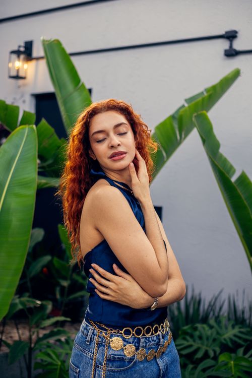 Free A fashionable woman poses gracefully in a lush São Paulo garden setting. Stock Photo
