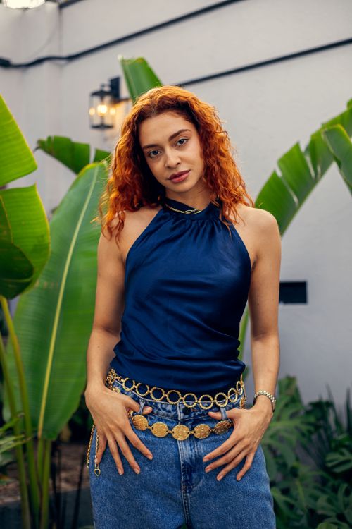 Free Fashionable woman with curly hair wearing a blue top and jeans, posing in São Paulo garden. Stock Photo