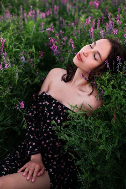 Serene woman in an off-the-shoulder dress relaxing in a lush lavender field during summer.