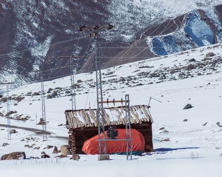 Tranquil snowy landscape with a wooden house in Minimarg, showcasing Pakistan's winter beauty.