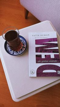 A book by Fatih Duman with a glass of tea on a small table. — photo by Ayşenur
