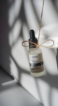 A glass serum bottle with a dropper casting shadows in natural light.