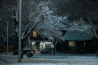 A serene winter night scene with snow-covered trees and houses in Toronto, Canada.