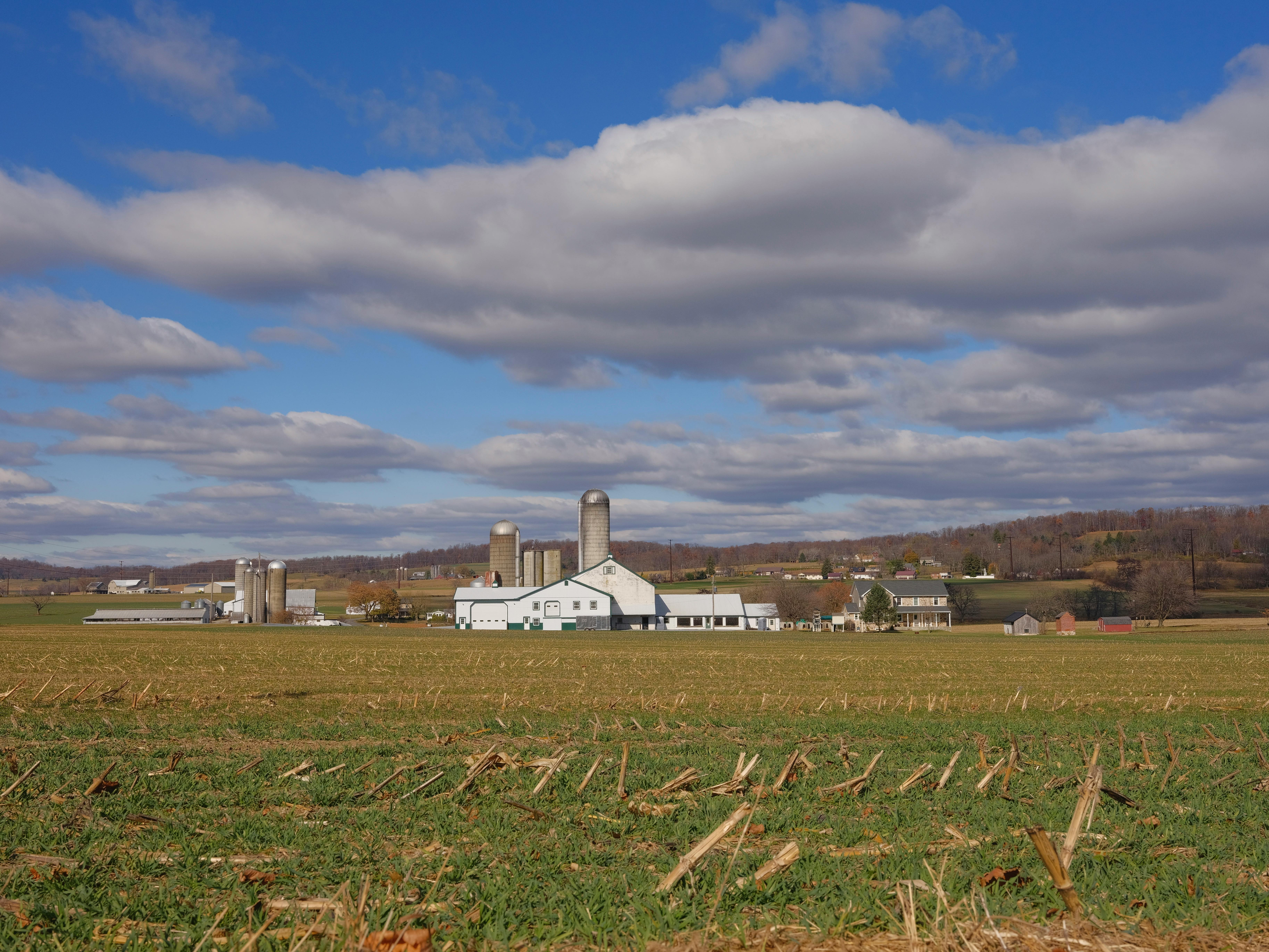 A picturesque rural scene of a farm with silos under a cloudy sky in Pennsylvania.