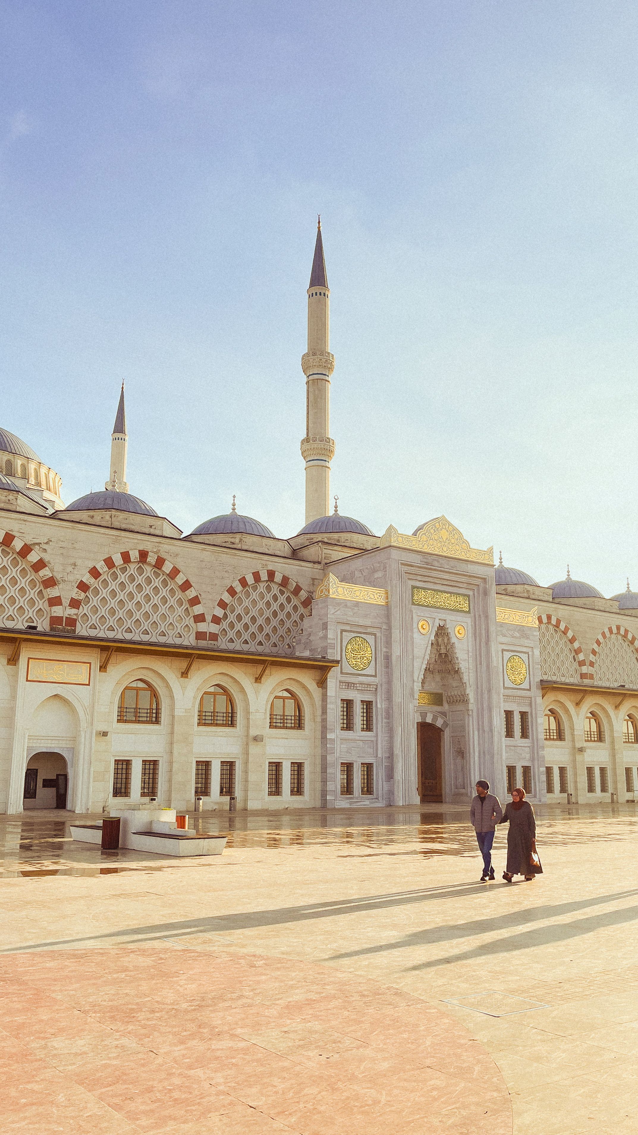 Stunning view of a mosque in İstanbul with blue sky and people in foreground.