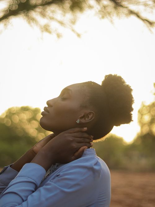 Free Silhouetted woman enjoying serene moment outdoors against sunset. Stock Photo