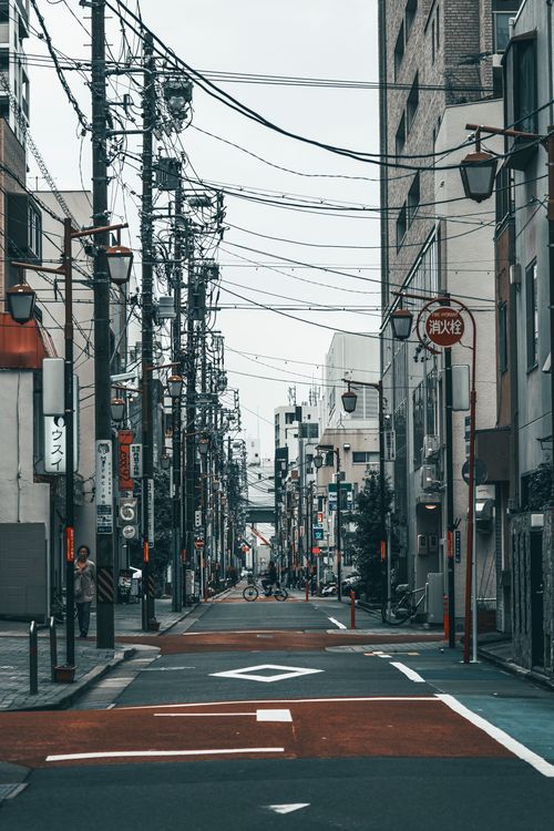 Free Japanese cityscape featuring an empty street lined with buildings and overhead power lines. Stock Photo