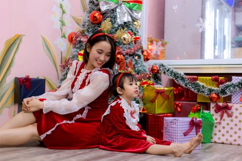 Free Mother and child in festive attire by a decorated Christmas tree with gifts. Stock Photo