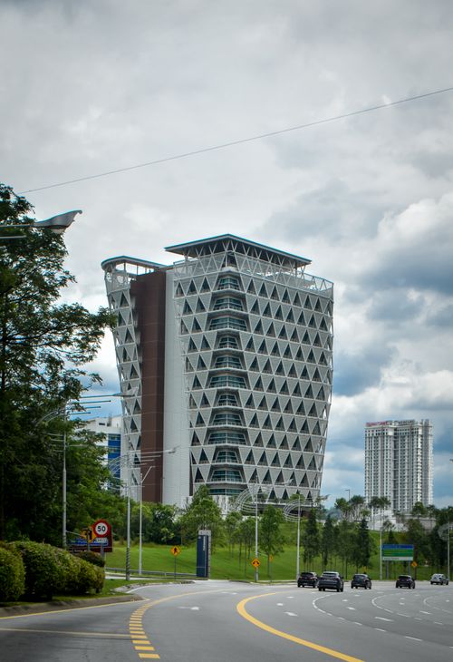 Free Distinctive modern building with triangular facade, set against a cloudy skyline in an urban area. Stock Photo