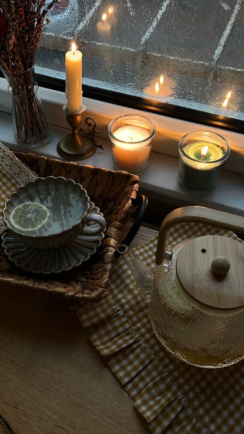 Free Warm indoor scene with candles, tea, and a rainy window, perfect for relaxing moments. Stock Photo