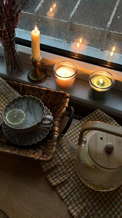 Free Warm indoor scene of tea, candles, and rain creating a cozy atmosphere. Stock Photo