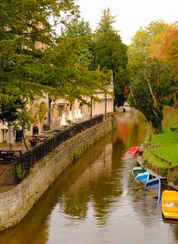 Charming Oxford canal lined with trees and colorful boats, ideal for a serene walk.