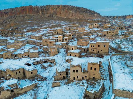 Aerial view of an abandoned village covered in snow, highlighting winter's tranquility.