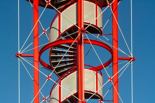 Free A striking red spiral staircase with geometric design against a clear blue sky. Stock Photo