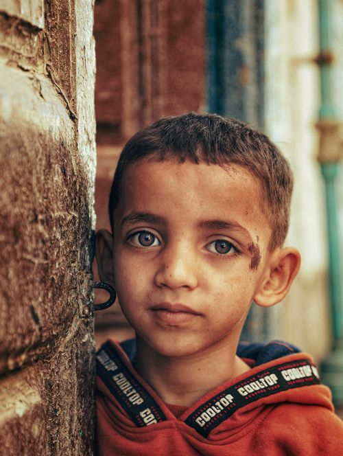 Free A thoughtful child gazes from a rustic urban setting, capturing sincerity and depth. Stock Photo