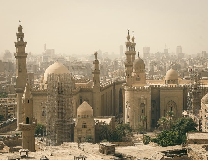 Panoramic view of Cairo featuring historic mosque architecture against the city skyline.