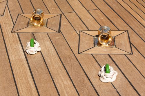 Free Close-up of yacht deck with brass cleats and tied rope, ideal for maritime or nautical themes. Stock Photo