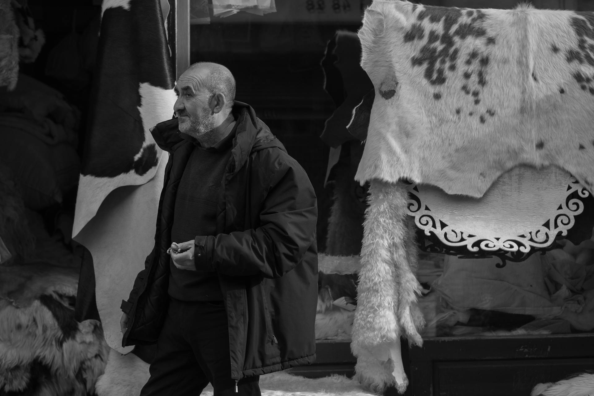 A man explores a market stall showcasing various leather goods and hides.