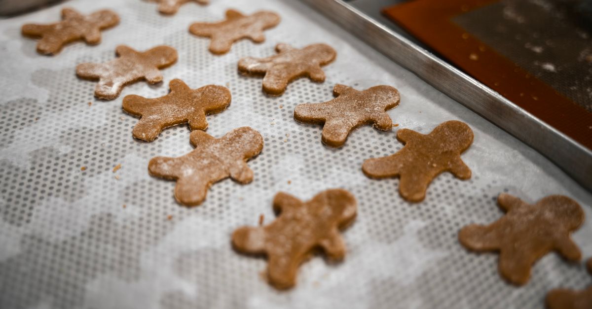Biscoitos de gengibre recém-cortados em uma assadeira, perfeitos para assar em festas de fim de ano.