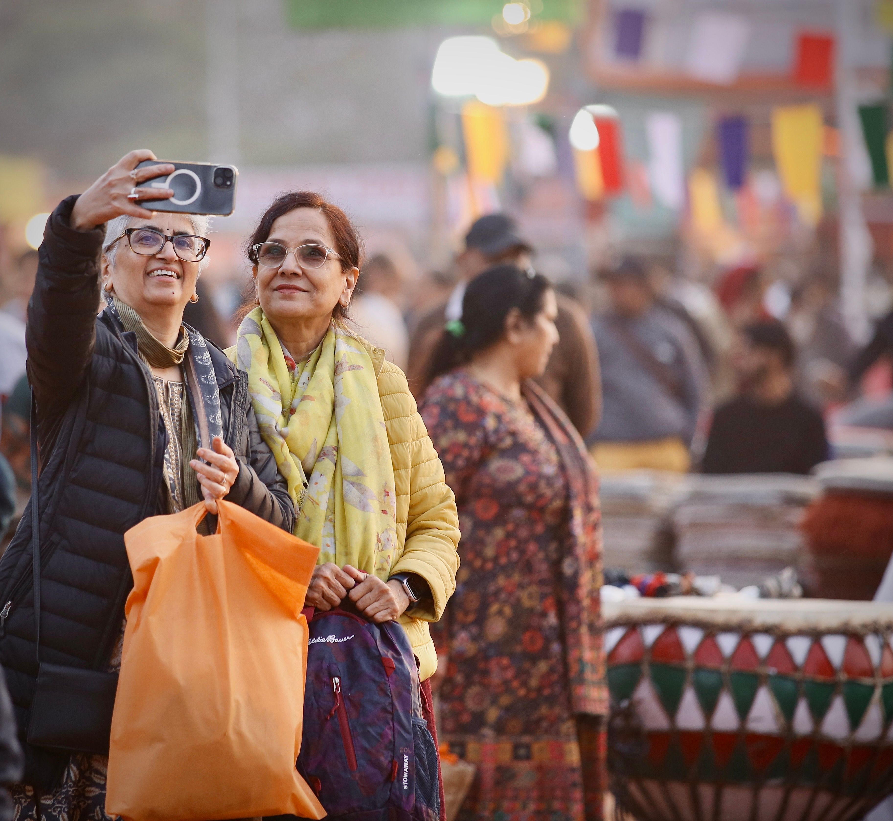 woman solo traveler smiling while checking phone in a bustling foreign market
