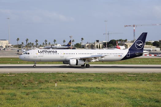 Lufthansa Airbus A321 jet taxiing on runway at a sunny airport with palm trees.