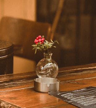 A warm and inviting cafe table with a small vase and red berries, creating a cozy atmosphere.