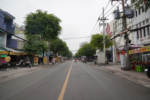 Quiet street lined with shops and trees in an urban setting.