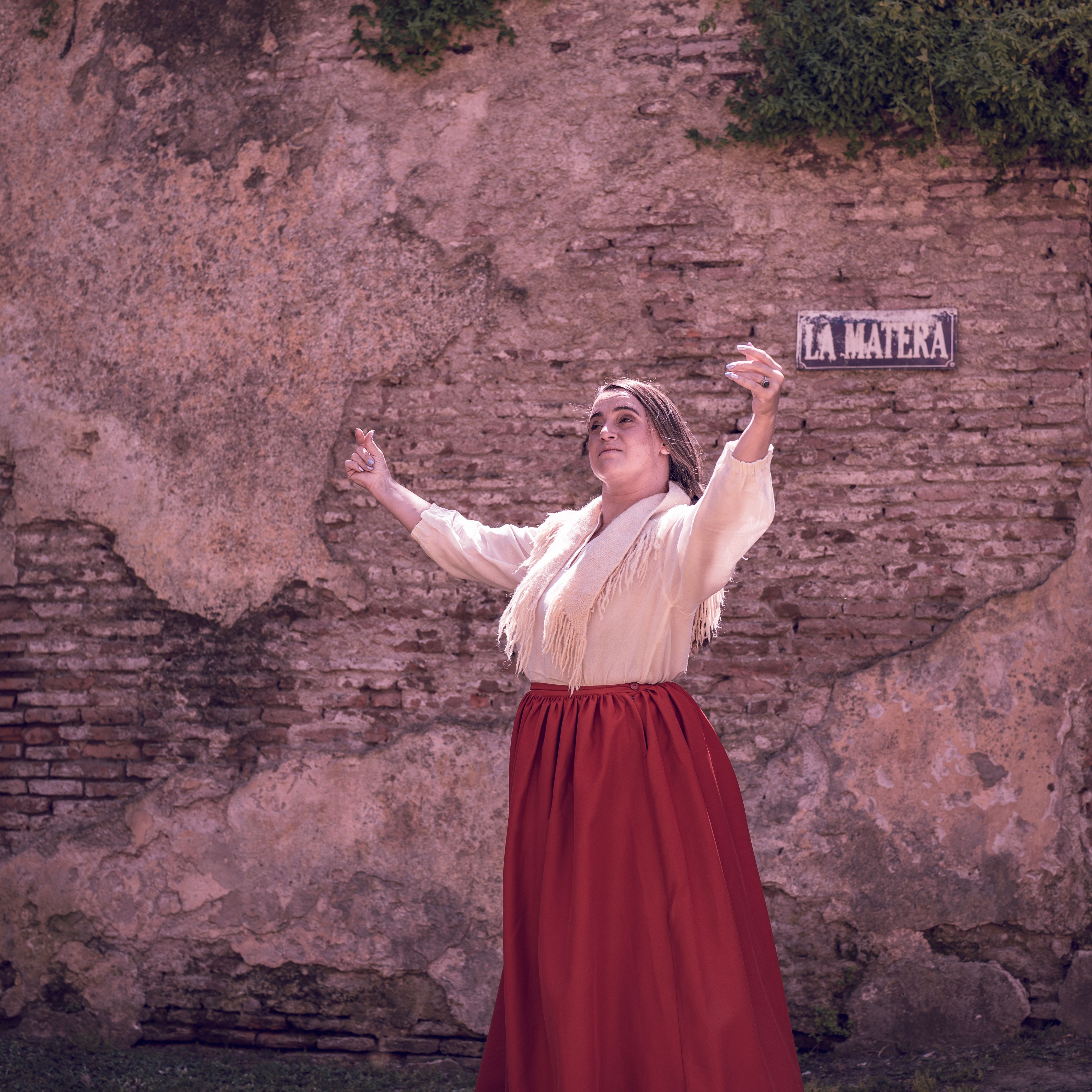 Woman performing traditional dance in Chascomús, Argentina, showcasing cultural attire against rustic backdrop.