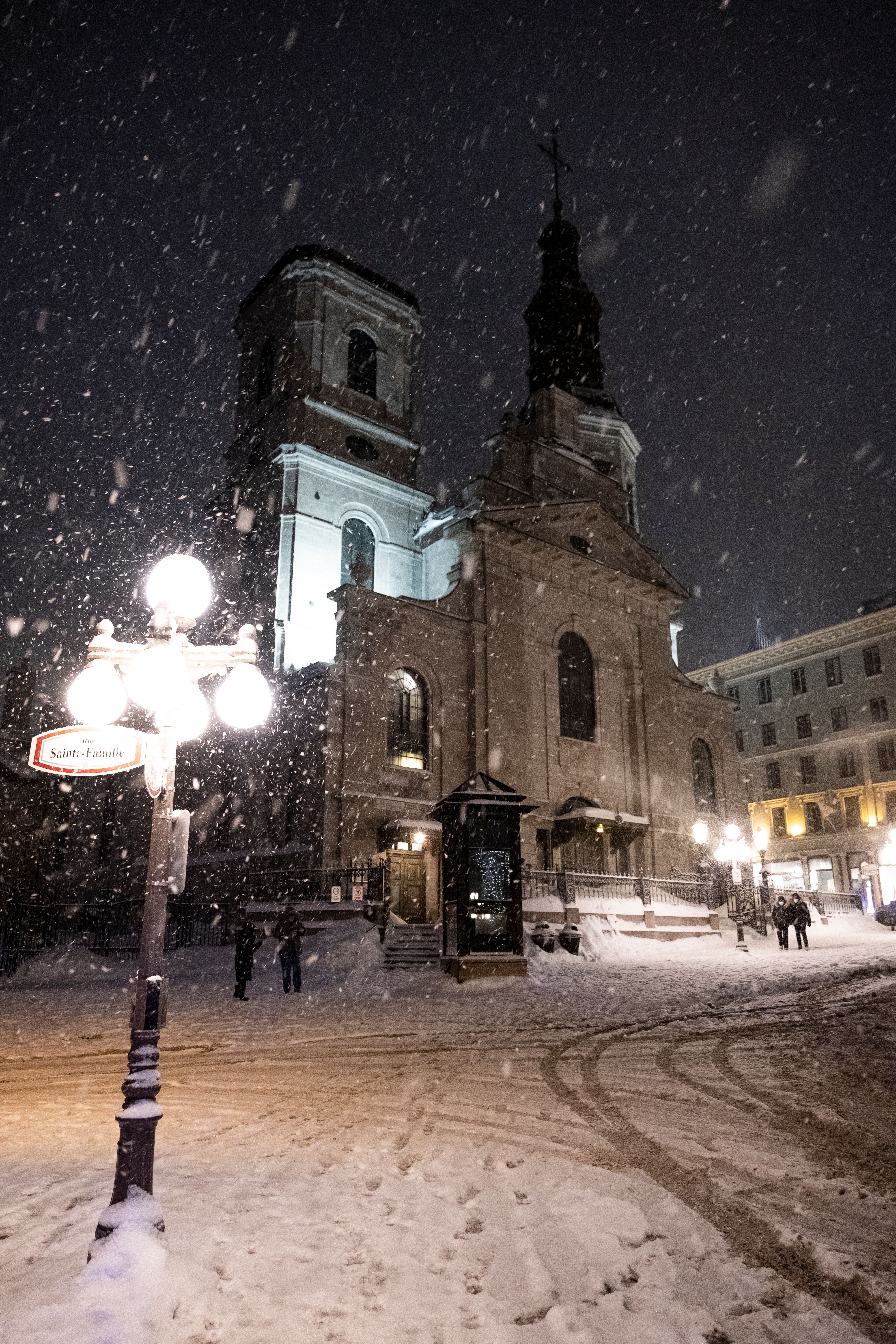 Majestic church in Québec City covered in snow on a winter night, creating a serene scene.