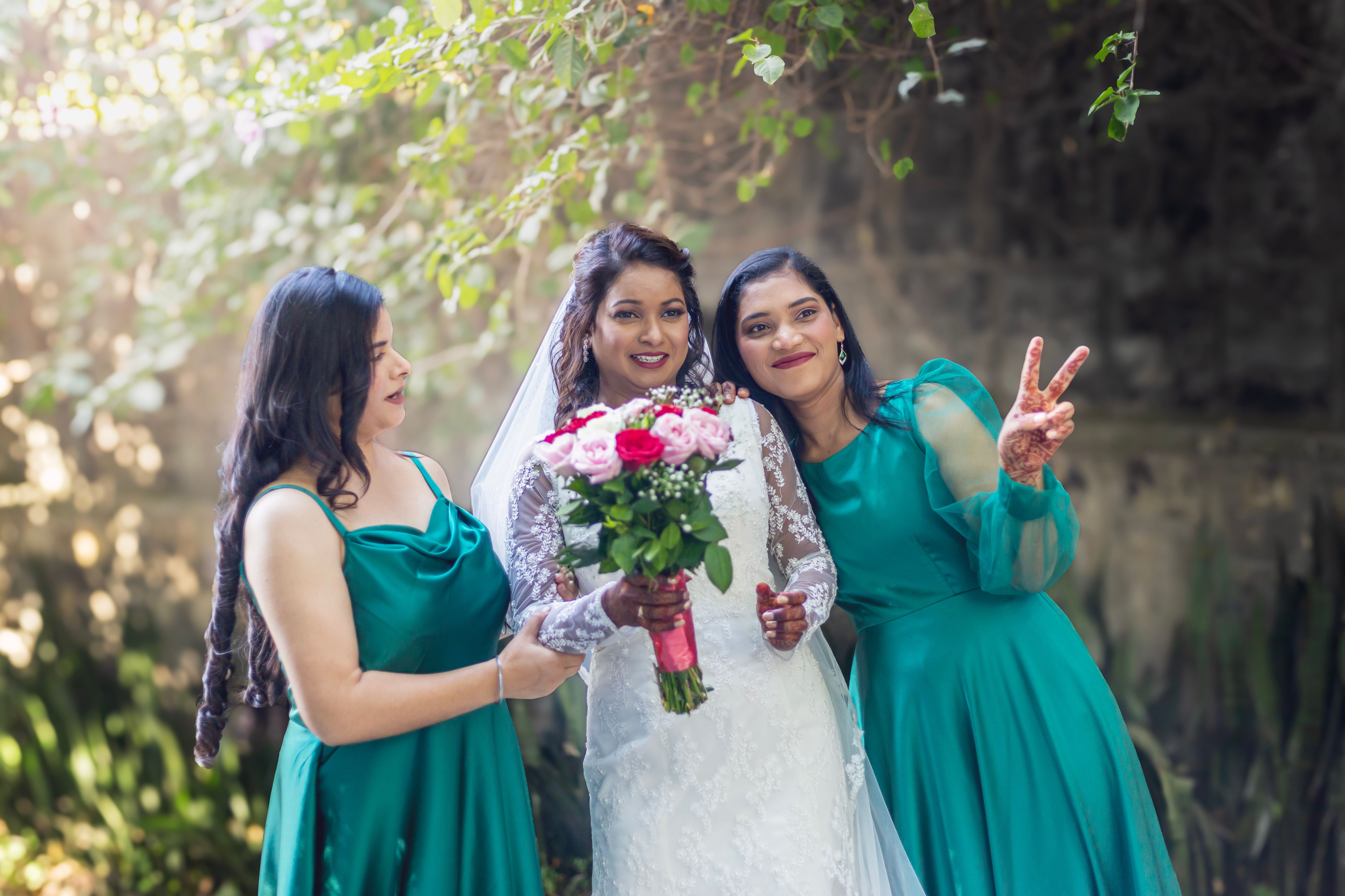 Mariée souriante avec ses témoins, bouquets champêtres en main, ambiance extérieure naturelle et douce