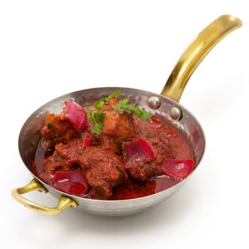 Delicious spicy chicken curry served in a traditional brass pan with vibrant colors.