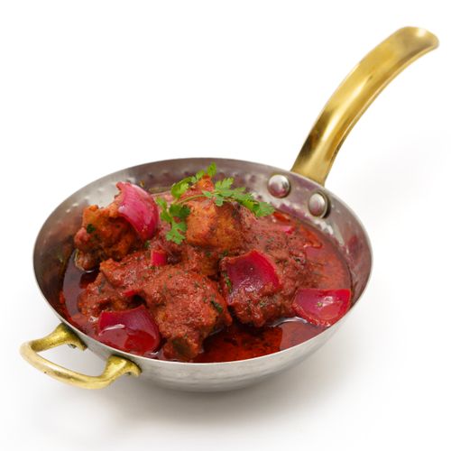 Free Delicious spicy chicken curry served in a traditional brass pan with vibrant colors. Stock Photo
