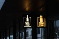 Illuminated 'Wine First' sign in Warsaw, reflecting a cozy nightlife scene.