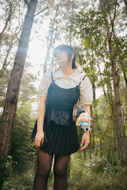 Free Portrait of a young woman standing in a forest with a cute backpack accessory. Stock Photo