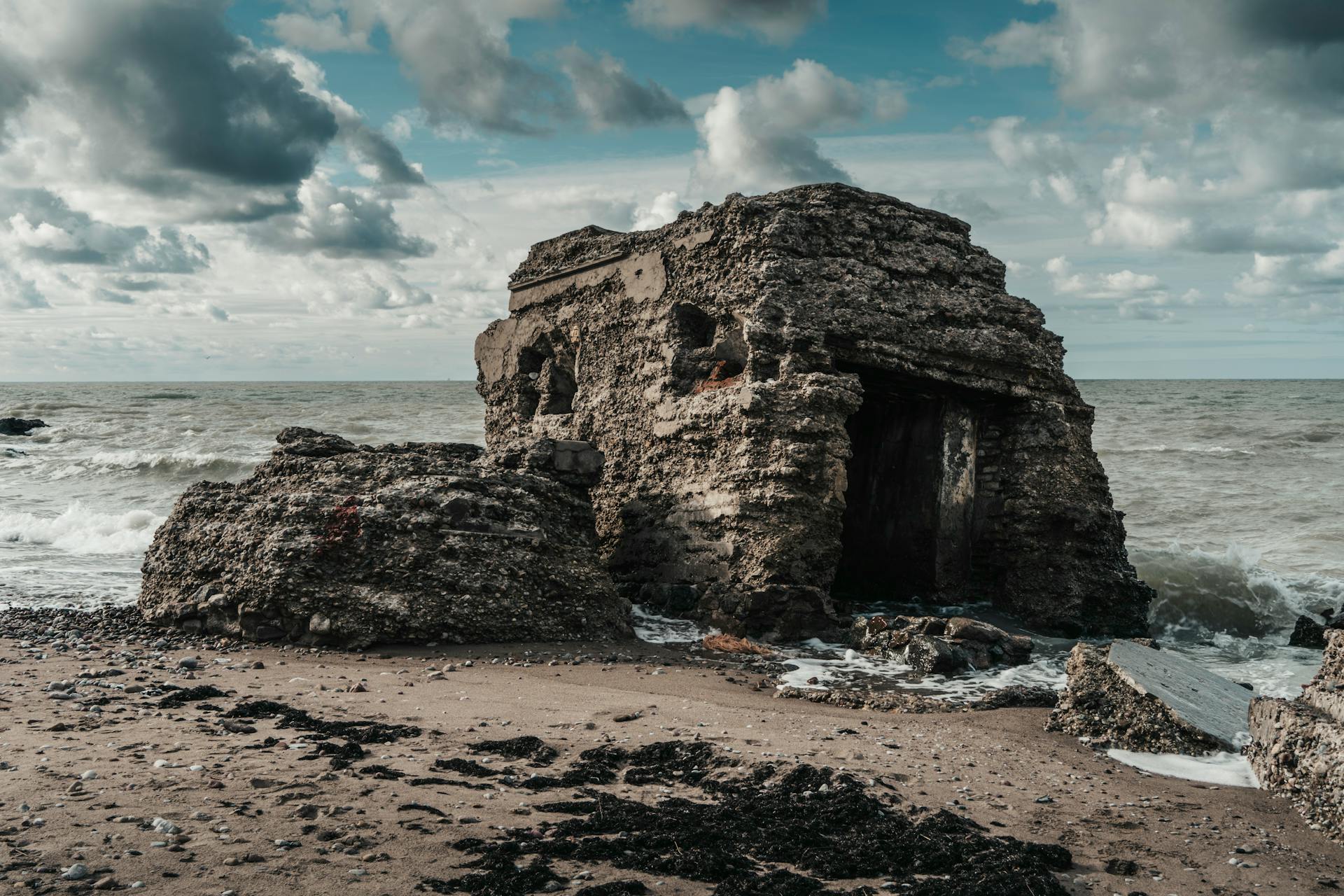 Old concrete bunker on a deserted beach under dramatic clouds. Captures weathered history and nature's raw beauty.