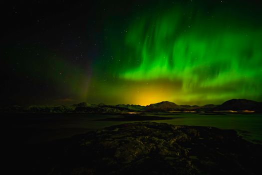 Breathtaking view of the aurora borealis illuminating the night sky above a serene Norwegian landscape.
