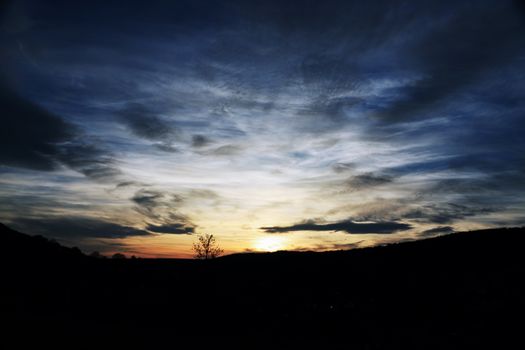 A breathtaking sunset with vibrant clouds over silhouetted hills, evoking peace.