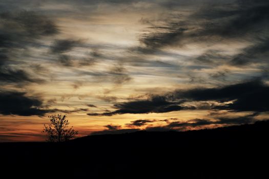 A captivating sunset with dramatic clouds over a silhouetted landscape.