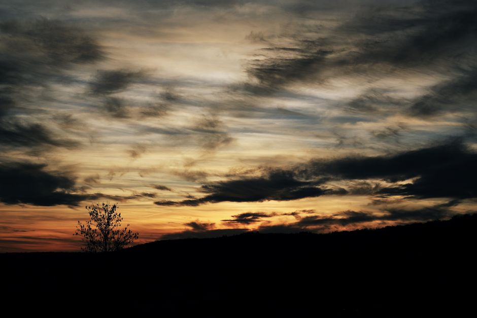 A captivating sunset with dramatic clouds over a silhouetted landscape.
