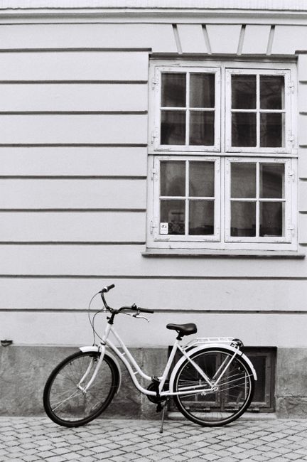 Black and white photo of a bicycle leaning against a windowed wall in Copenhagen.