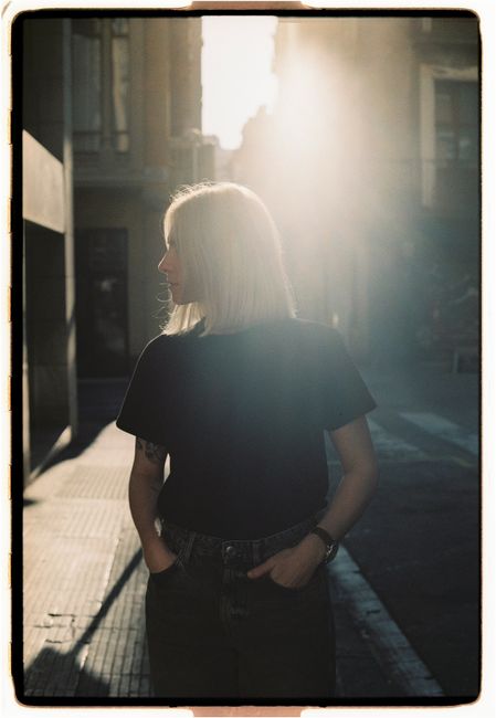 Silhouette of a woman in an urban alley, bathed in warm sunset light.