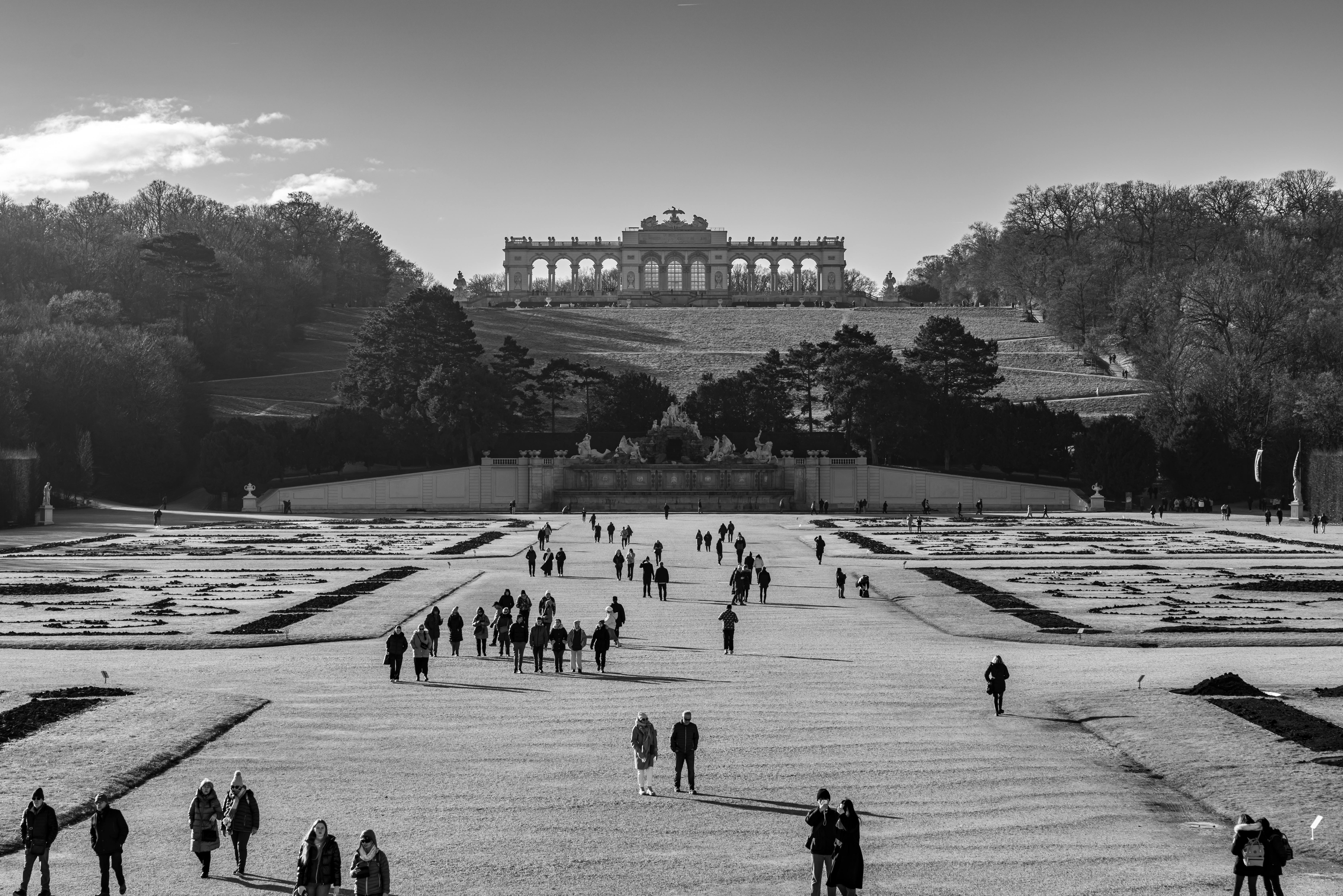 People strolling through Schönbrunn Palace Gardens in Vienna, Austria, with Gloriette in the background.