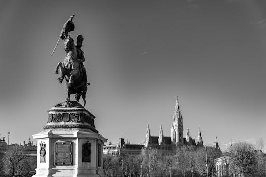Black and white shot of an equestrian statue with Vienna's cityscape, featuring the iconic Rathaus.