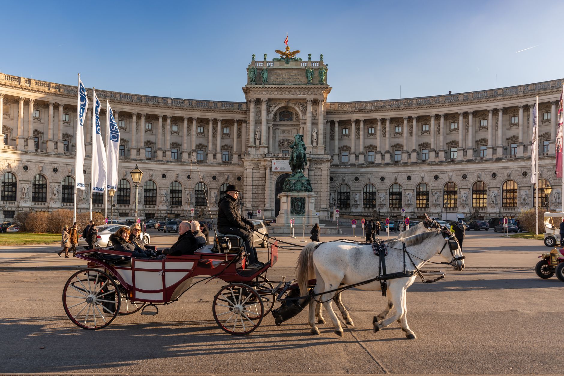 Picturesque horse-drawn carriage ride passing the iconic Hofburg Palace in Vienna, Austria.