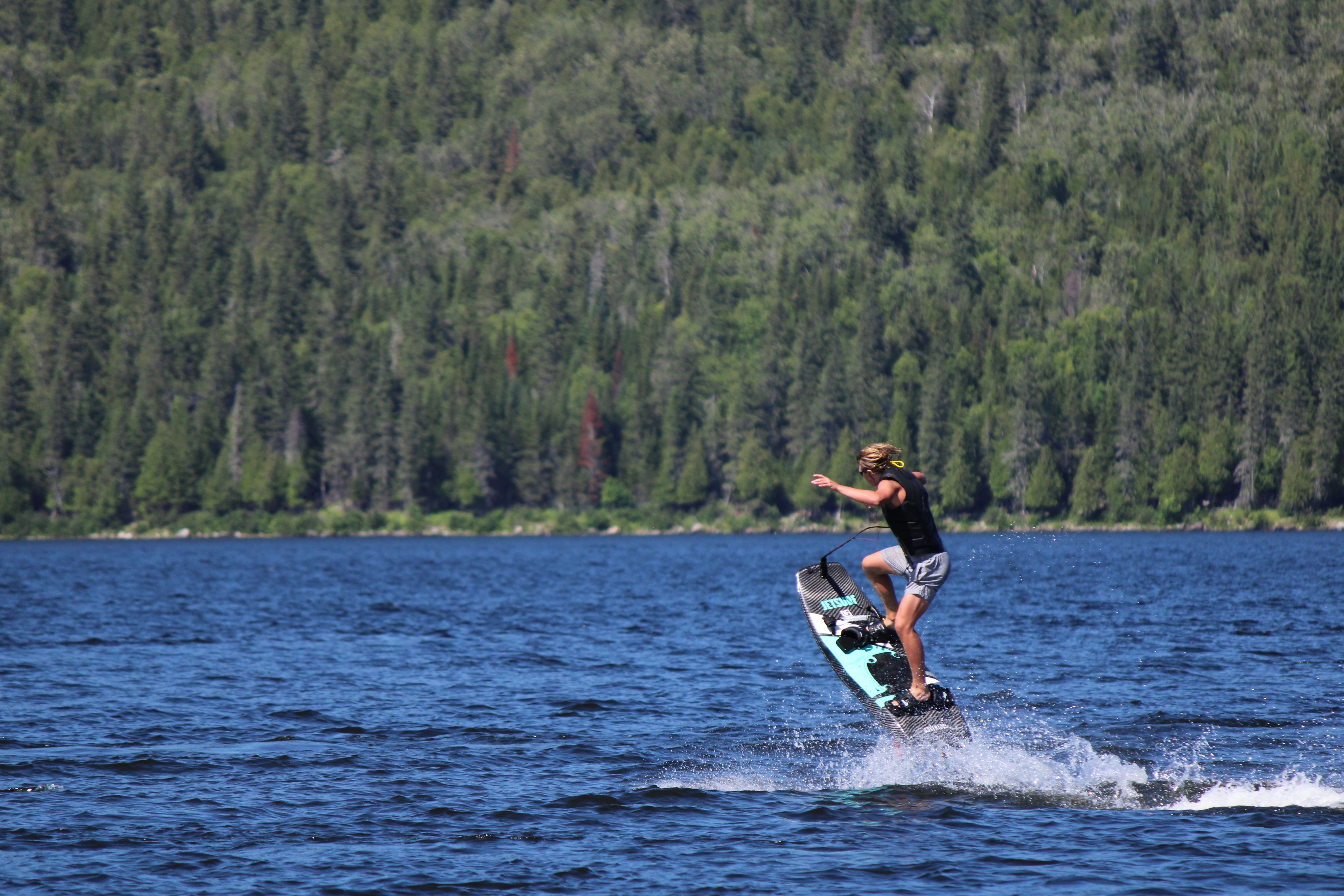 A person jet surfing on a lake surrounded by lush forest, capturing a summer adventure.