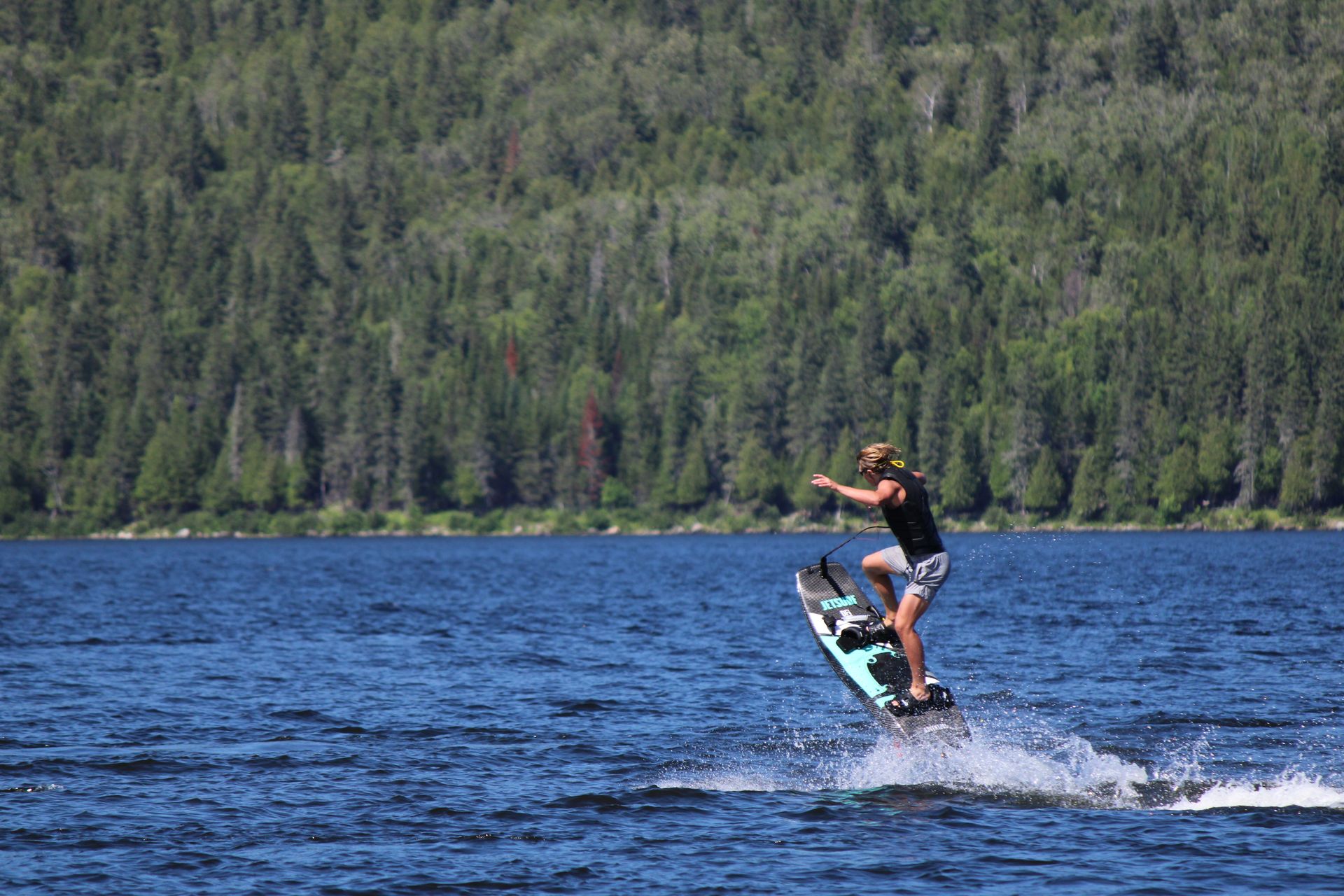 A person jet surfing on a lake surrounded by lush forest, capturing a summer adventure.
