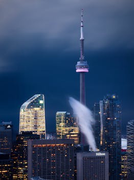 Dramatic night view of Toronto's skyline with the iconic CN Tower and illuminated skyscrapers.